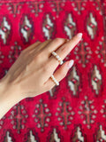 Hand wearing a pearl ring on a red patterned fabric background
